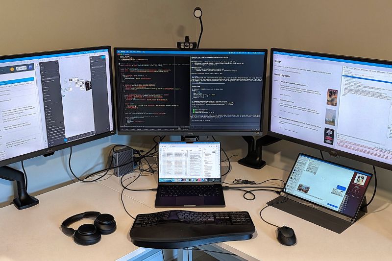 Desk with three monitors, a laptop, and a portable display